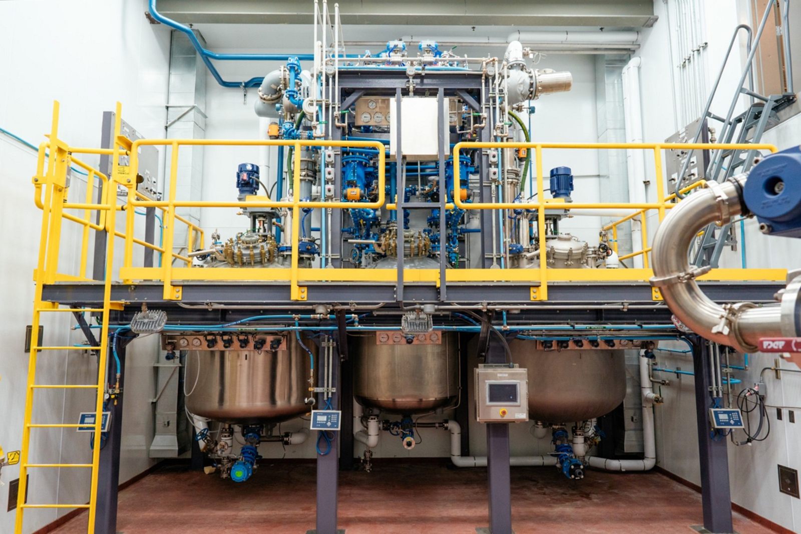 cGMP manufacturing suite with three reactors beneath an elevated platform